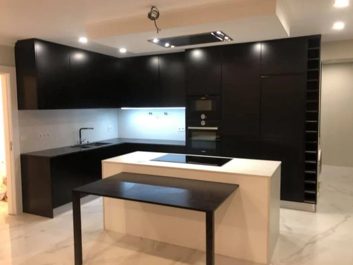 Cozinha lacada a preto com ilha e bancada em pedra