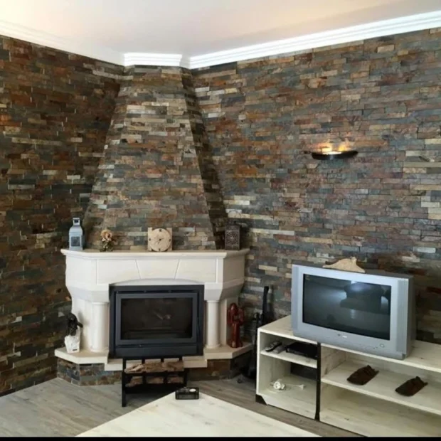 After — living room with a fireplace and stone walls