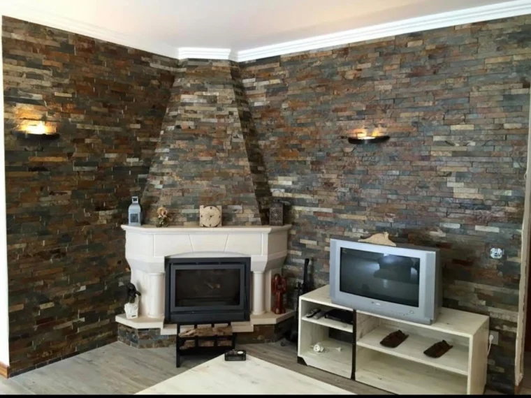 After — living room with a fireplace and stone walls