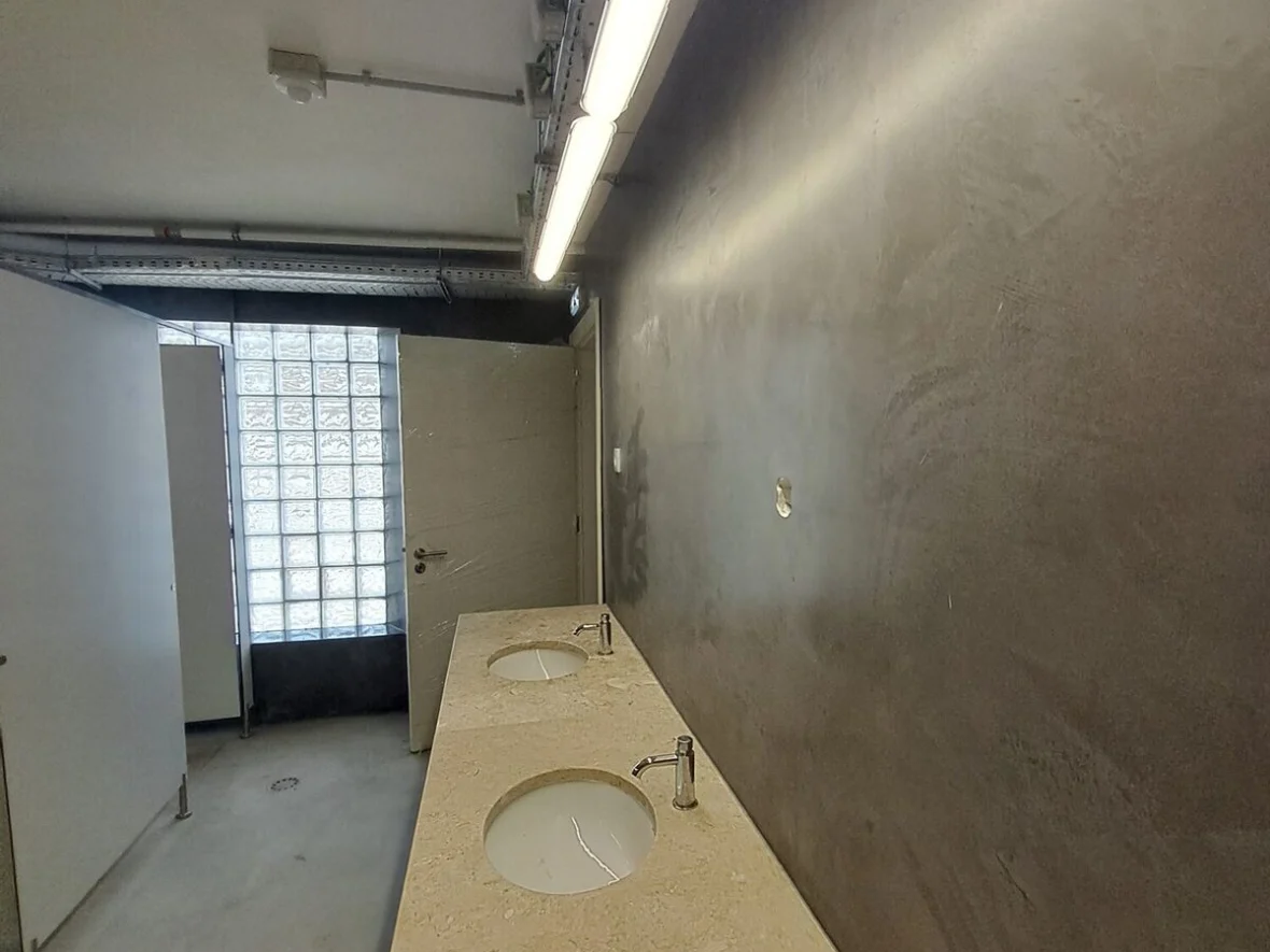 Washroom corridor with a dark microcement wall